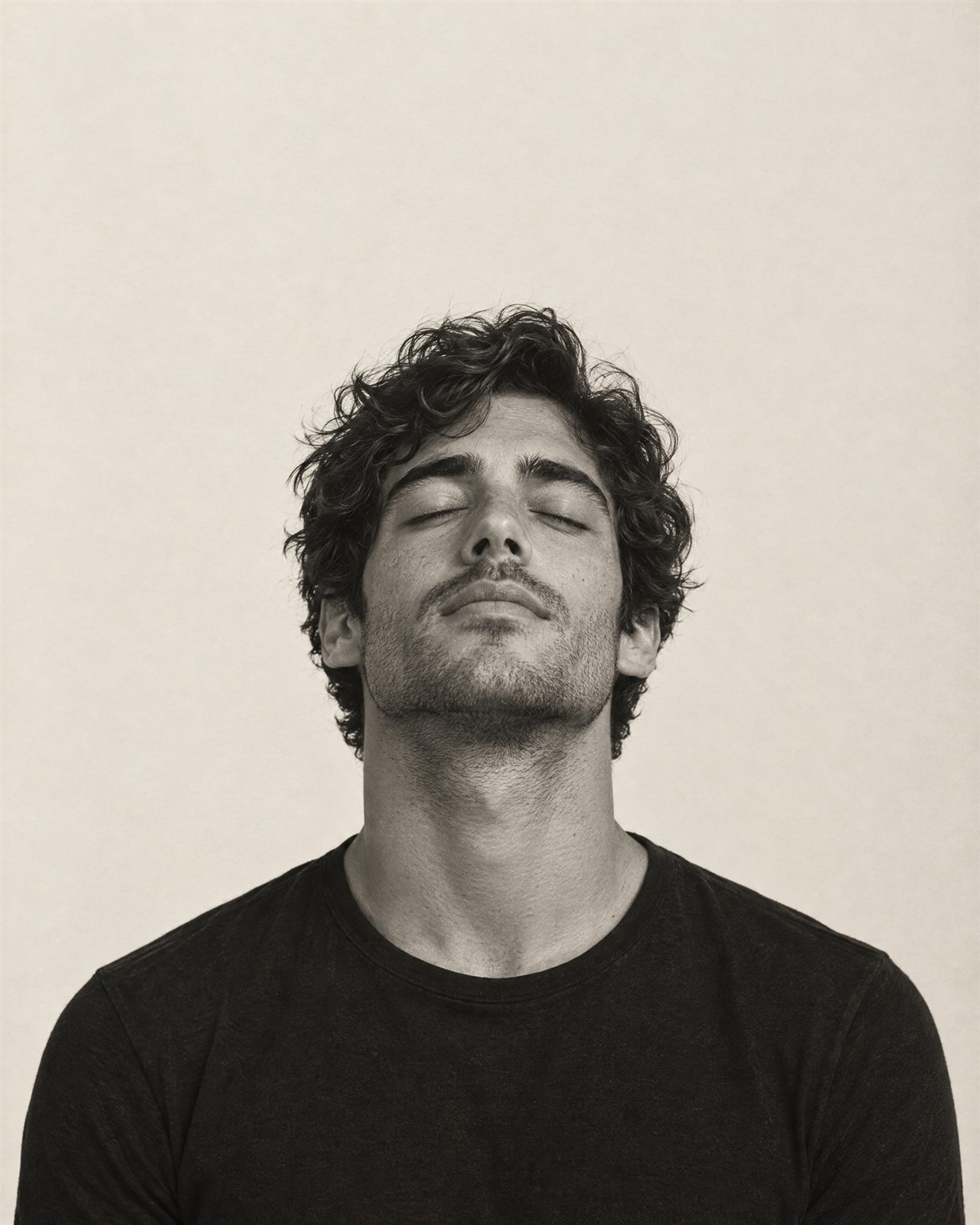 Black and white portrait of a man with his eyes closed, head tilted up